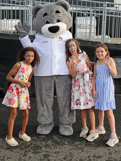 Dr. Bear and three girls pose for a photo outside of Loudoun United FC field.