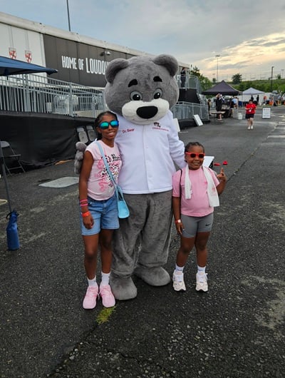 Dr. Bear and two girls pose for a photo outside Loudoun United FC field.