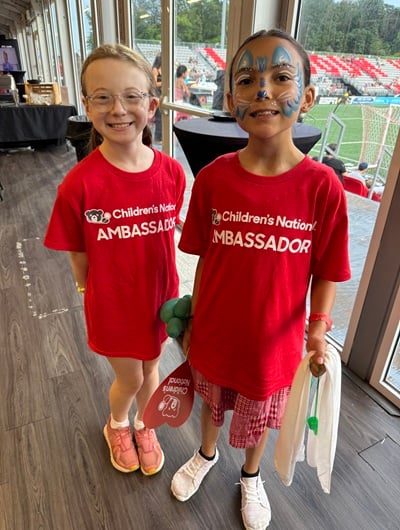 Two Children's National patient ambassadors smile inside the Loudoun United FC facility.
