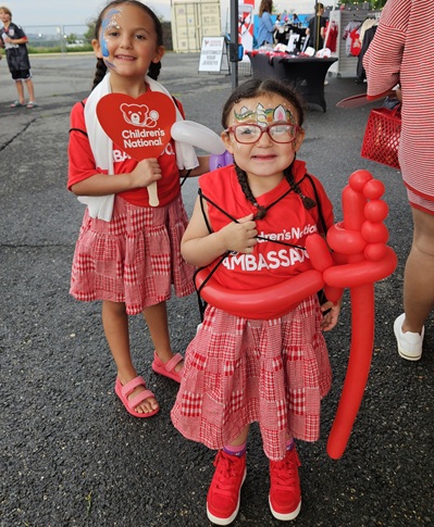 Two Children's National patient ambassadors smile outside the Loudoun United FC field.
