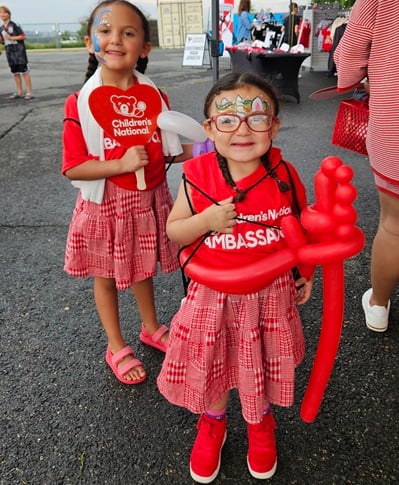 Two Children's National patient ambassadors smile outside the Loudoun United FC field.