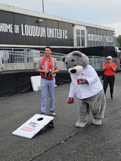 Cardiologist Wayne Franklin, MD, MBA, senior vide president of the Heart and Lung Center at Children's National, plays corn hole with Dr. Bear outside Loudoun United FC field.