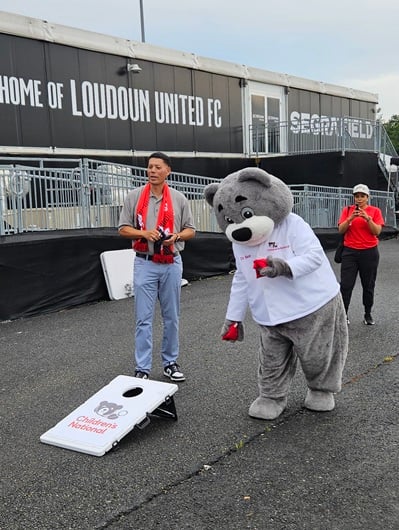 Cardiologist Wayne Franklin, MD, MBA, senior vide president of the Heart and Lung Center at Children's National, plays corn hole with Dr. Bear outside Loudoun United FC field.
