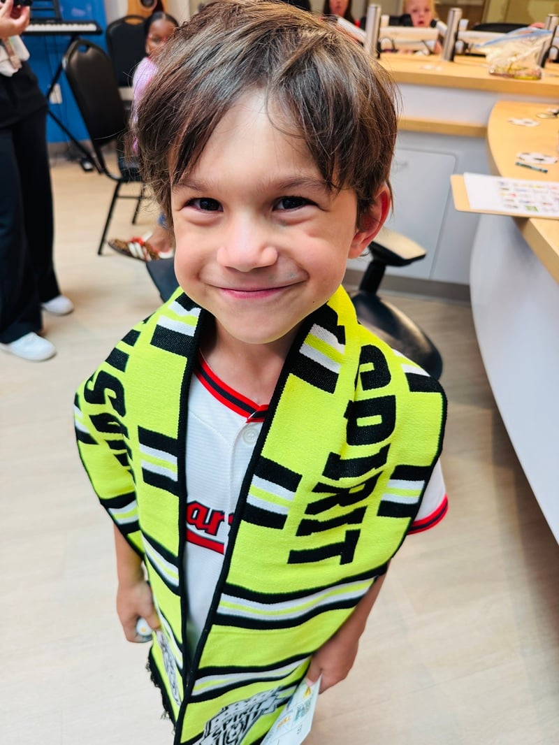 A child wearing a florescent yellow and black Washington Spirit soccer scarf smiles during a visit by Spirit players and leaders at Children's National Hospital.