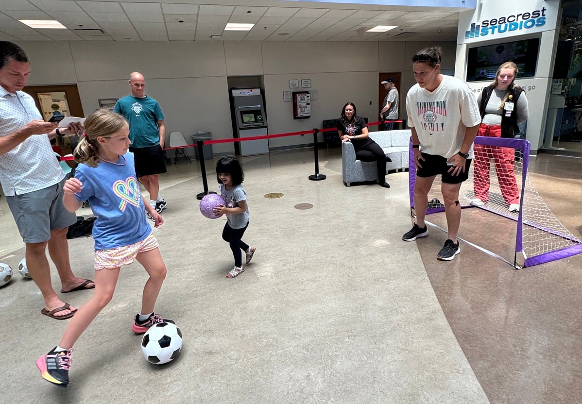 A girl takes dribbles a soccer ball toward a mini goal set up in the Costco Wholesale Atrium at Children's National Hospital during a visit by Washington Spirit leaders and players.