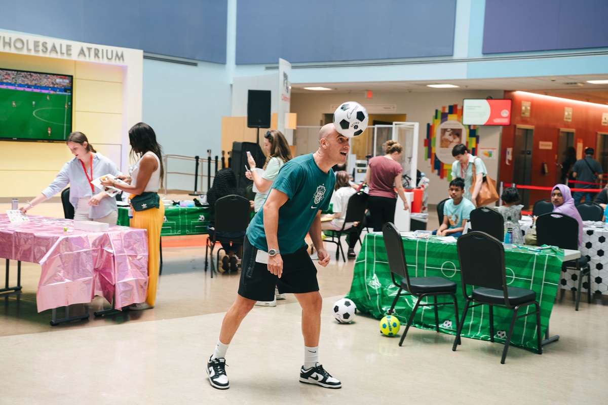 Washington Spirit Head Coach Adrián González plays with a soccer ball in the Costco Wholesale Atrium at Children's National Hospital during a visit by team leaders and players.