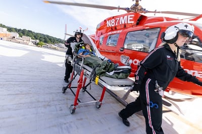 Emergency transport team on helicopter pad with patient on gurney