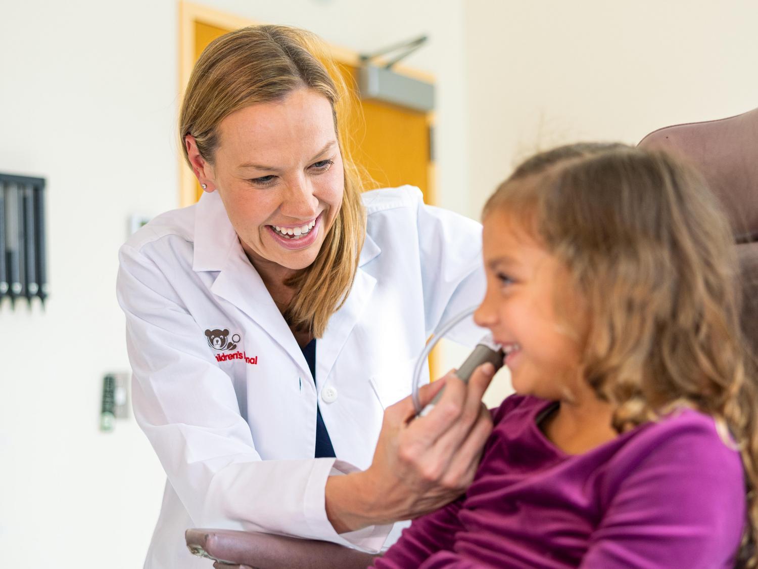 Otolaryngologist looking in young girl's ear