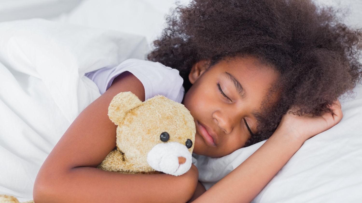 young girl sleeping and holding teddy bear