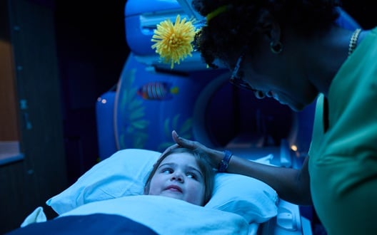 A nurse comforts a young girl before the child enters an MRI machine