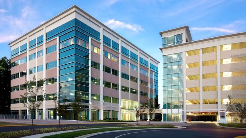Exterior view of the Children's National medical office building at 3023 Hamaker Court, featuring a multi-story glass office building connected to a parking garage.