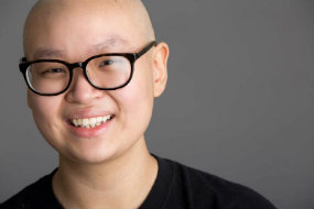 Bald Carly wearing black glasses and smiling