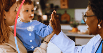 Mom holding a child while he high fives his doctor.