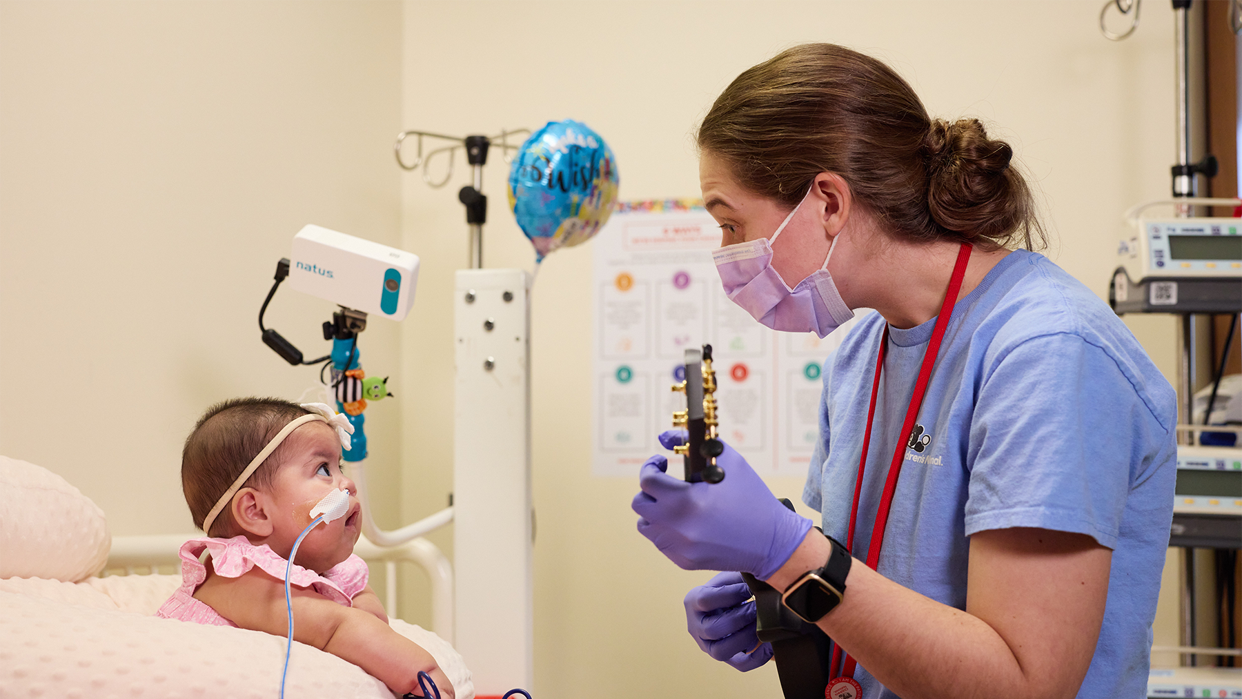 Music therapist playing the guitar for a baby in the nicu