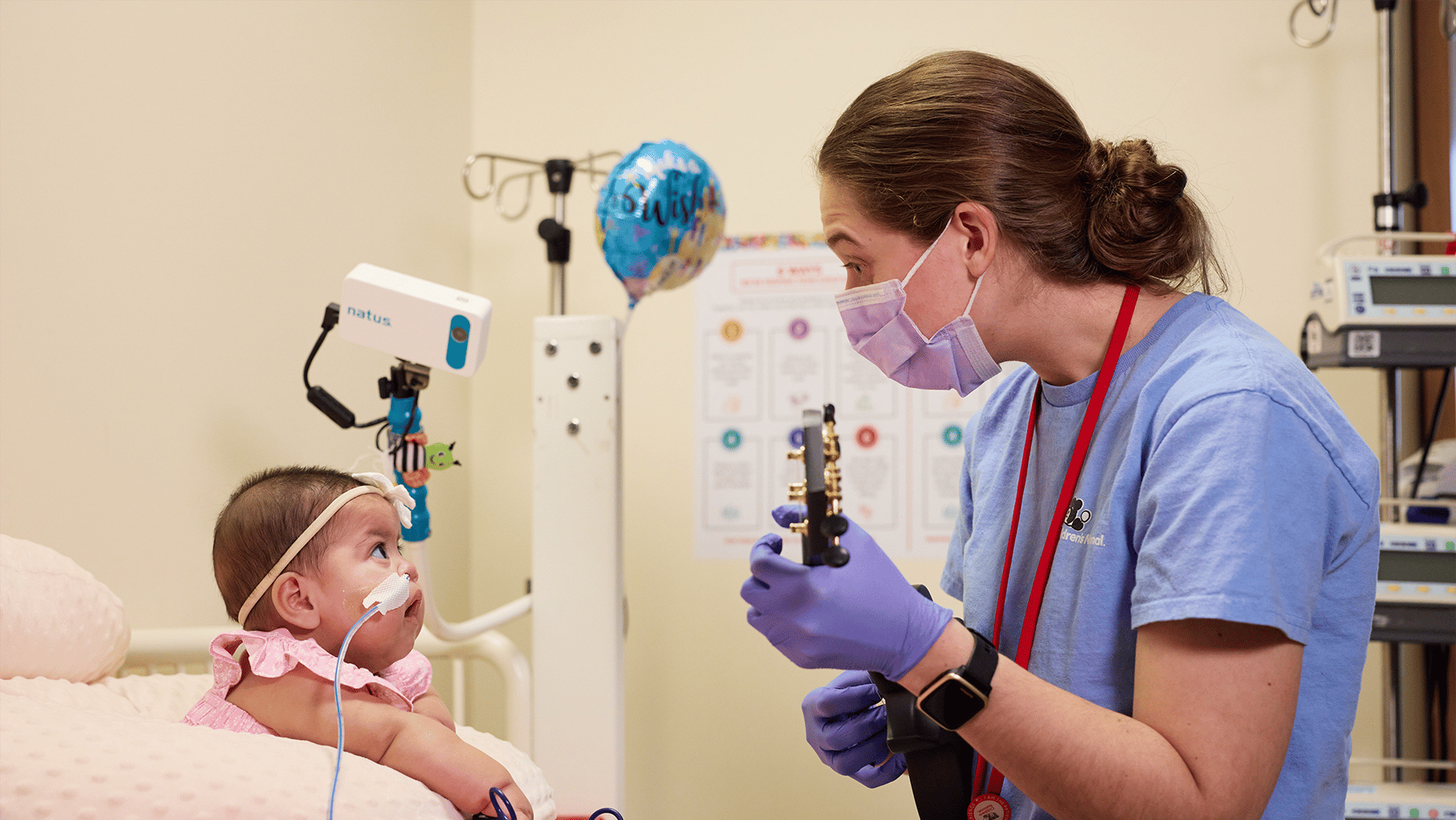 Music therapist playing the guitar for a baby in the nicu