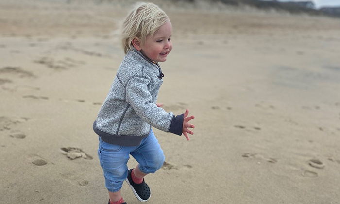 Photo of a toddler-aged patient running on a beach.