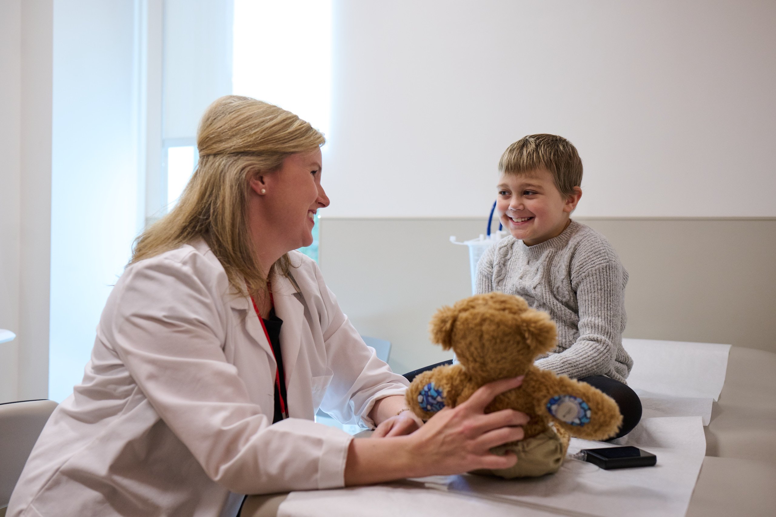 A Children's National provider holding a stuffed animal toy interacts with a young patient.