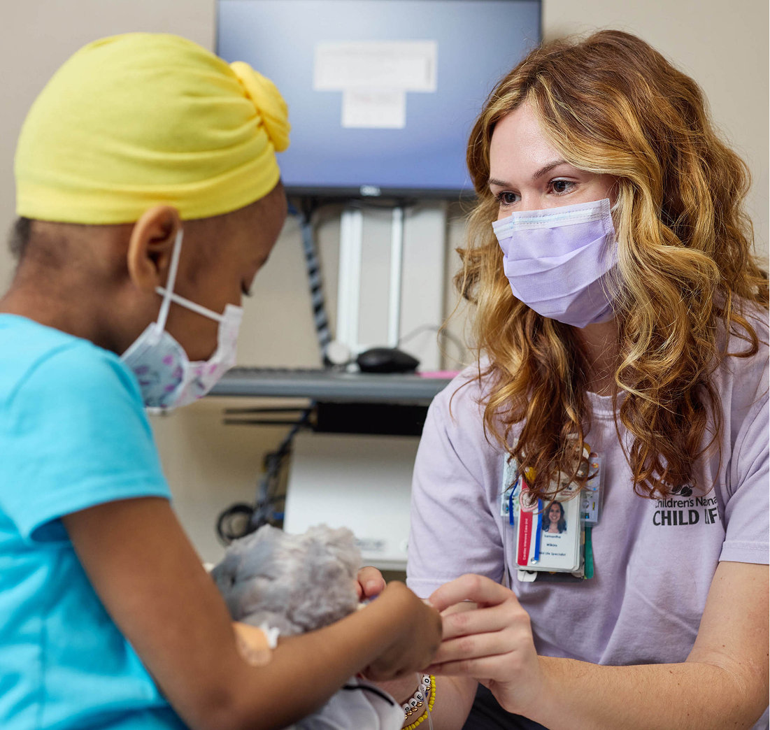 Children's National employee and a patient playing with a stuffed animal toy.