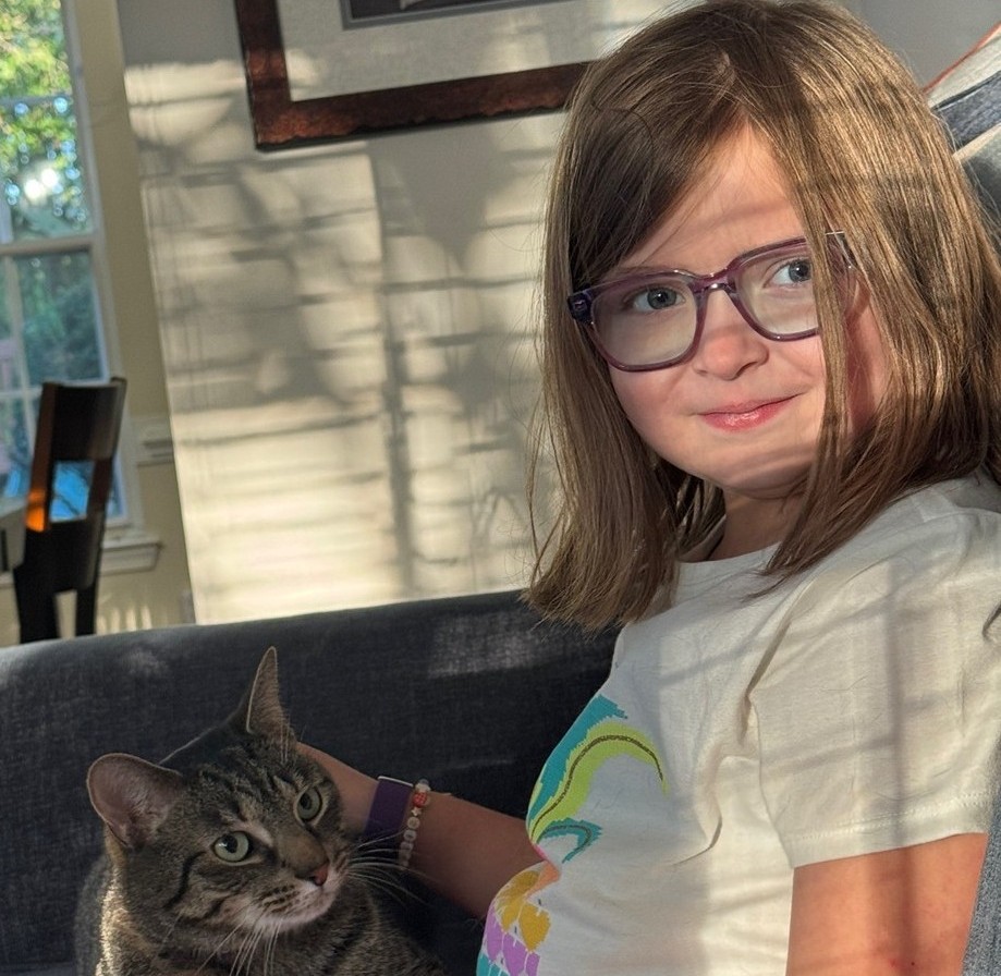 Ellie petting a cat that is sitting on her lap.