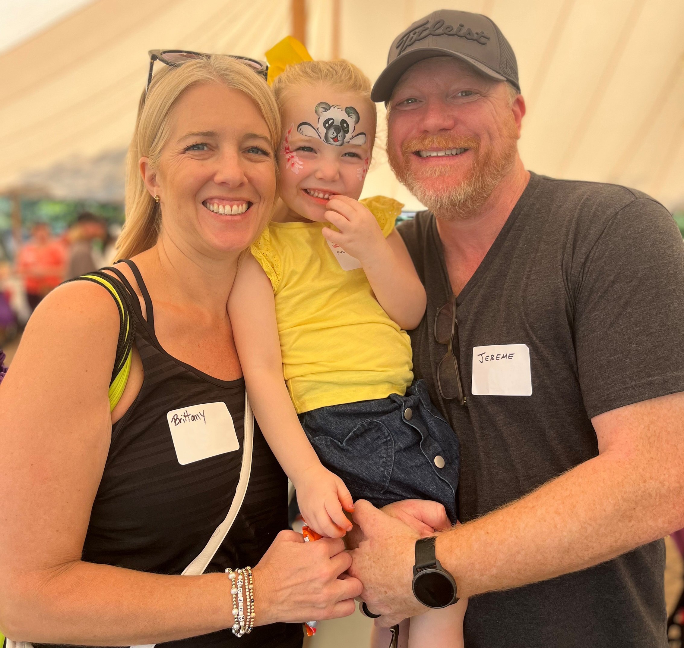 An older Fiona posing with her parents at a NICU reunion event.