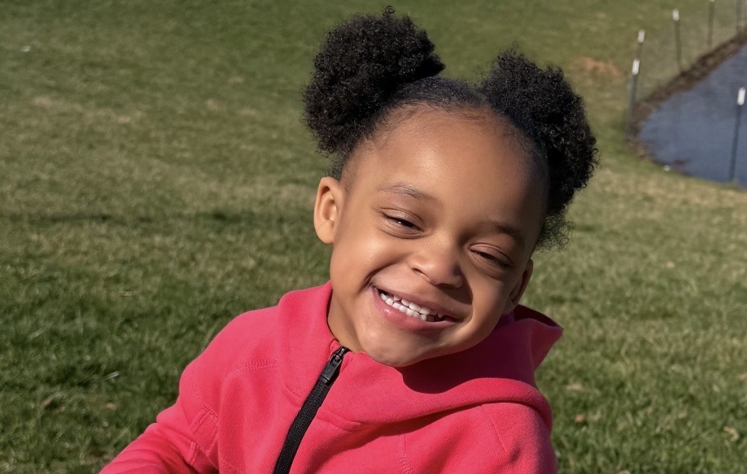 Gianna smiling while standing on a scooter.