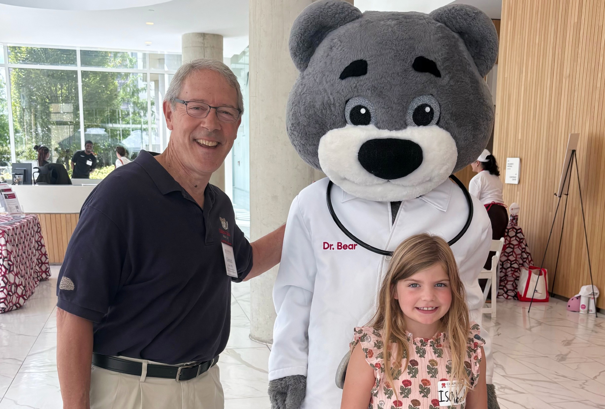 Isabel and her medical provider, Dr. Gioia, posing with the Dr. Bear mascot.