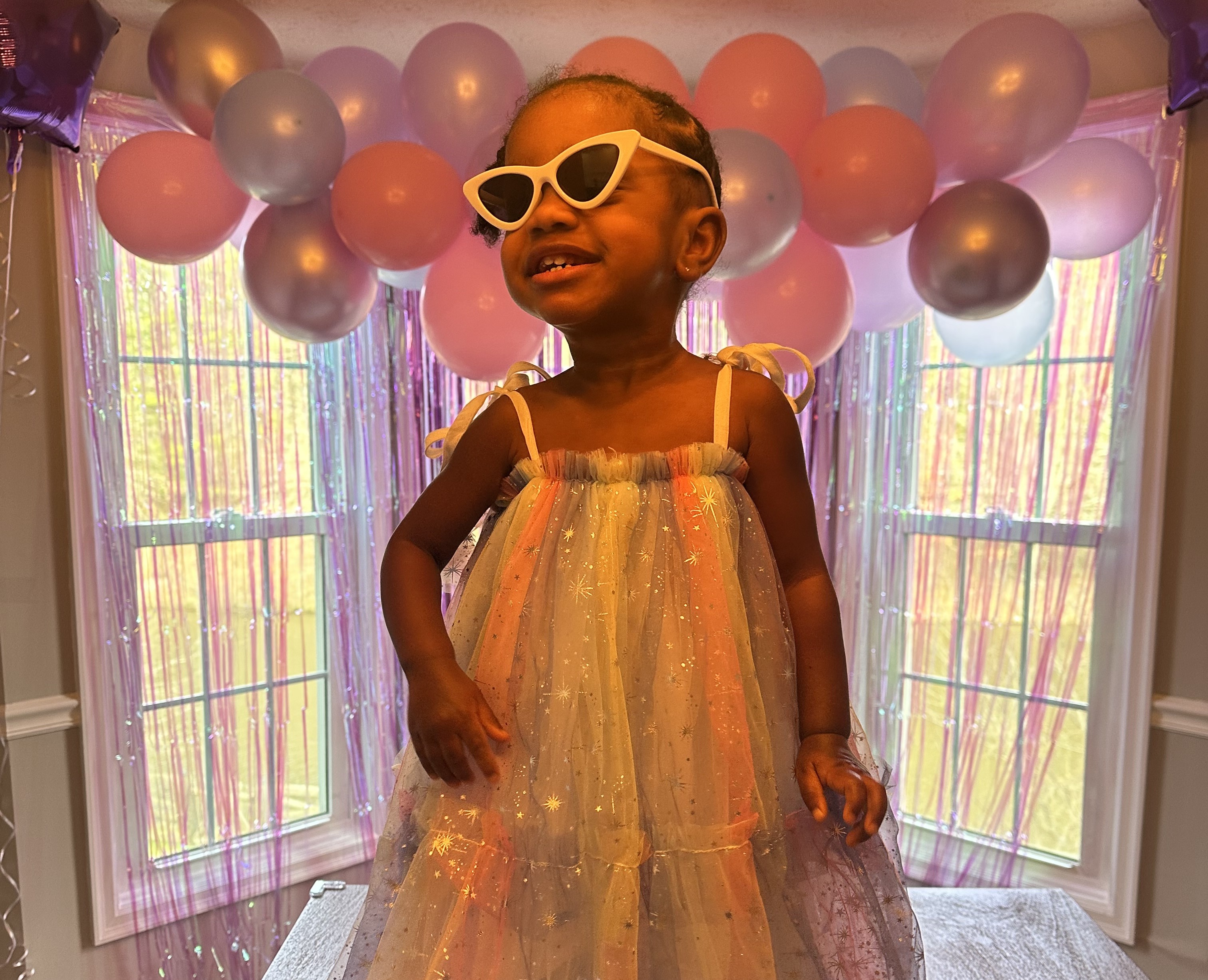 Melaina as a toddler dancing while wearing sunglasses at her Two Fancy party.