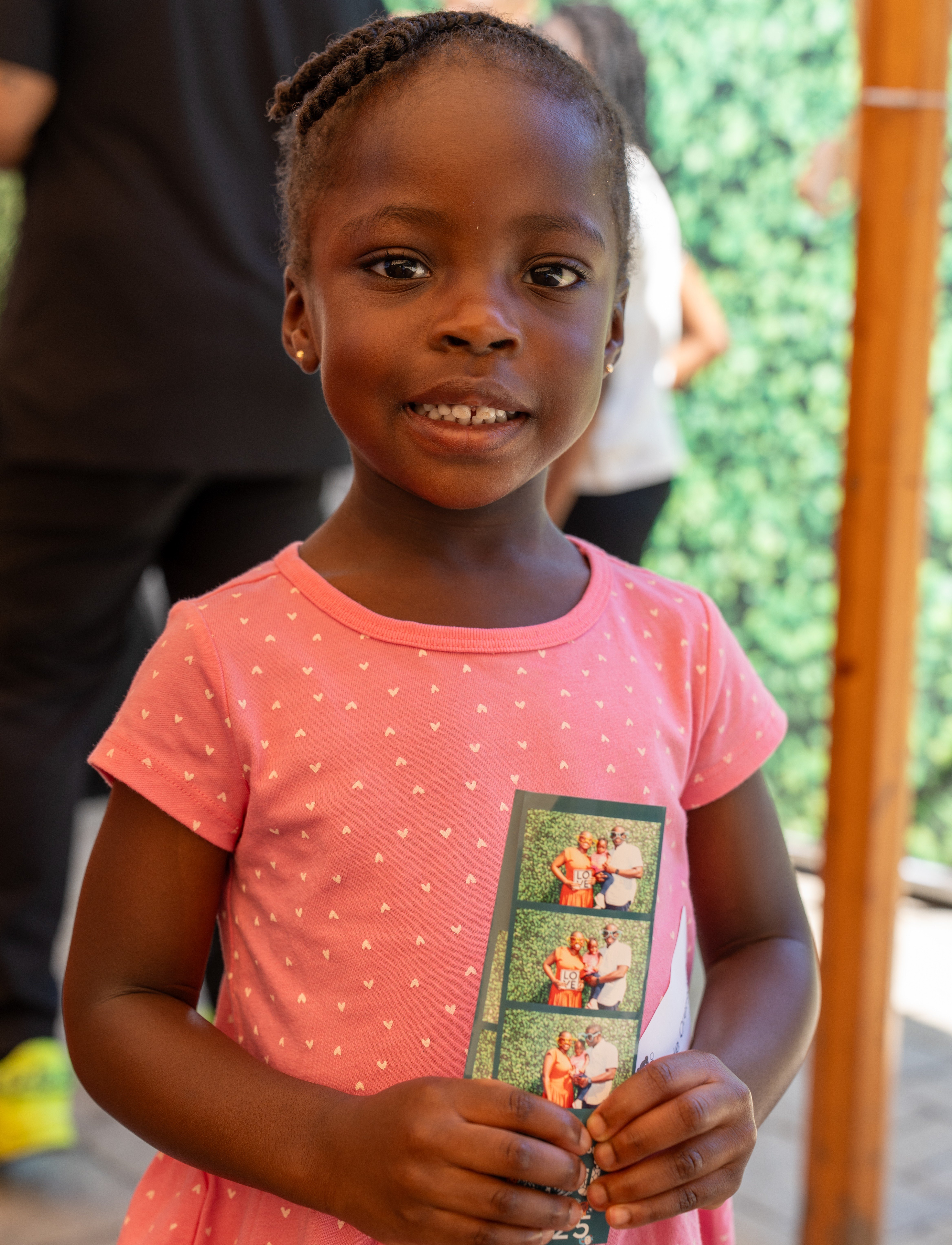 An older Mide smiles while holding photo booth images at the 2025 NICU reunion.