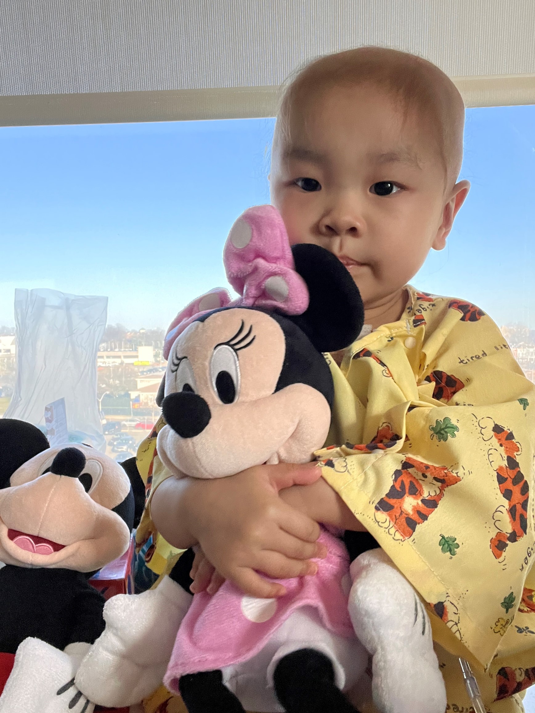 Snuggled up with a Minnie plush doll, Mikaela finds comfort during treatment.